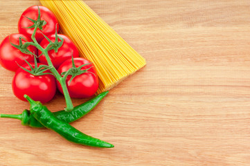 Bunch of spaghetti pasta, green hot peppers and Ripe tomatoes on