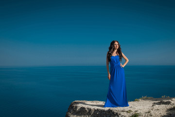 Fototapeta na wymiar Beautiful woman standing on a cliff over blue sky. Brunette girl