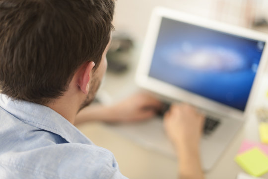rear view of a man examining his computer's screen