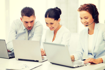 group of people working with laptops in office