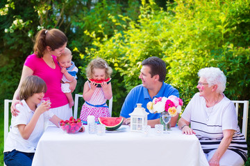Happy family eating fruit in the garden