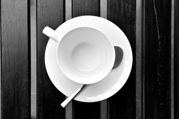 A cup of coffee on a wooden table in an outdoor cafe.