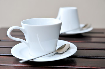 A cup of coffee on a wooden table in an outdoor cafe.