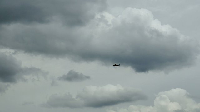View of a flying helicopter in dark sky clouds