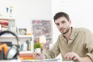 Fototapeta premium young student sitting at his desk and taking notes