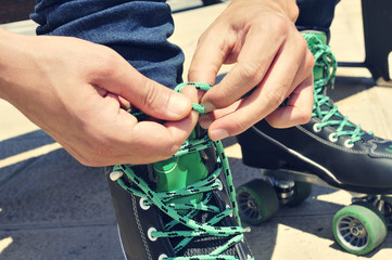 young man tying his roller skates, with a filter effect