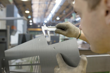 Worker Measuring Detail with Vernier Caliper in Factory Workshop