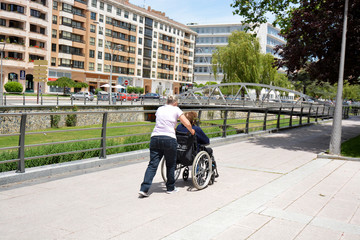 mujer empujando una silla de ruedas por la calle