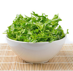 Watercress in bowl on bamboo