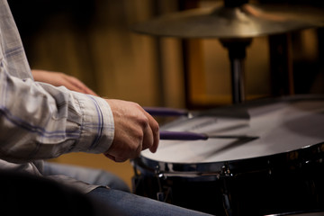 Hands of the man playing a drum set in dark colors