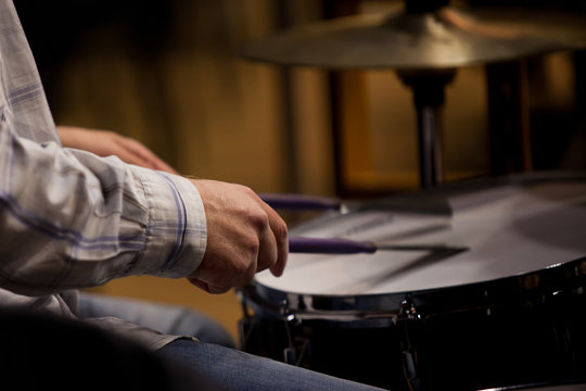 Hands of the man playing a drum set in dark colors