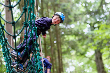 Happy boy enjoying a climbing adventure in activity park