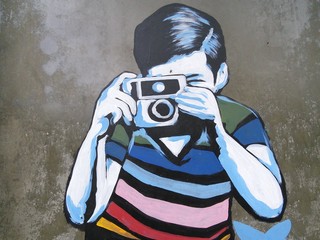 Graffiti art of boy taking photo.