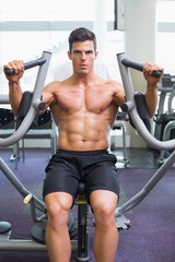 Fototapeta na wymiar Muscular man working on fitness machine at the gym