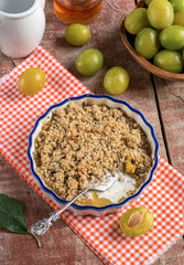 Plum crumble with cream on wooden background