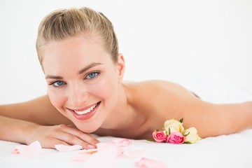 Obraz na płótnie Canvas Pretty blonde lying on massage table with rose petals