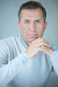 Portrait Of Mature Handsome Man Against Gray Wall