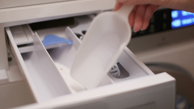 close up of a woman hand pouring detergent powder