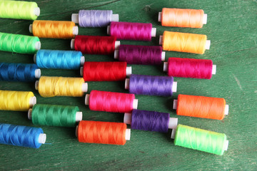 Multicolor sewing threads on wooden background