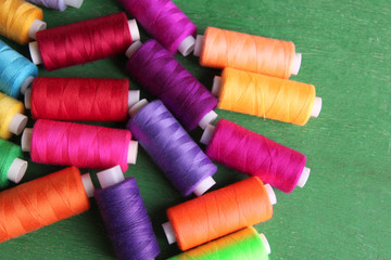 Multicolor sewing threads on wooden background
