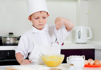 Young boy chef adding ingredients to his bowl