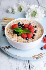 Tasty oatmeal with berries on table close-up