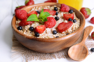 Tasty oatmeal with berries on table close-up