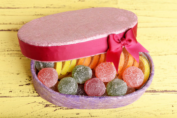 Present box with sweets on wooden background