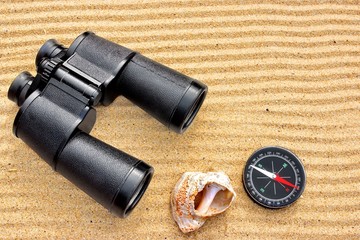 Sea Binoculars and Compass on Sand