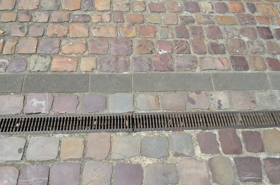 Fototapeta Rue pavée avec grille d'évacuation des eaux pluviales