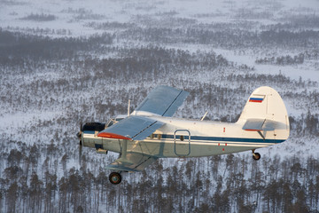 Old plane flying over the snow-covered plain