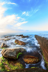 Sunrise on beach with rocks and sea
