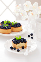 Tartlets with cream and blueberries, selective focus
