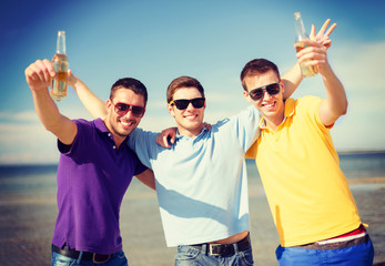 male friends on the beach with bottles of drink