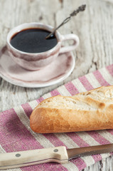 Baguette and cup of coffee on the wooden board