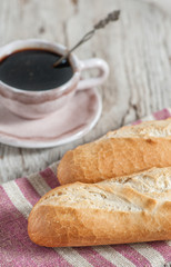 Baguette and cup of coffee on the wooden board