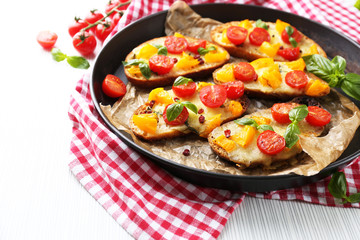 Tasty bruschetta with tomatoes in pan, on table