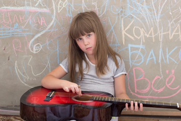 Girl 6-7 years old, sitting with a guitar