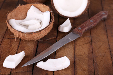Broken coconut with knife on wooden background