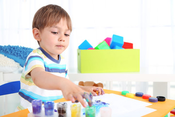 Cute little boy painting in room