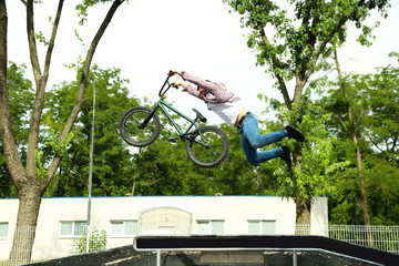 Young boy jumping with his BMX Bike at skate park
