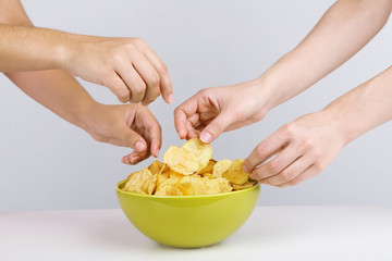 Hands of people take chips from bowl