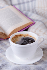 Cup of coffee on plaid with book
