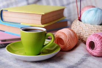 Cup of coffee and yarn for knitting on plaid with books