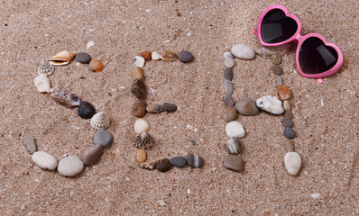 Fototapeta na wymiar Word sea made from sea shells and stones on sand