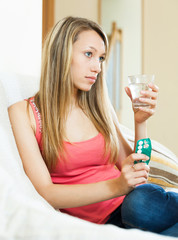 Woman with serious face sitting on sofa with pills