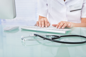 Doctor Typing On Computer Keyboard In Clinic