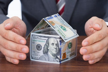 Businessman Sheltering House Made With Bank Notes