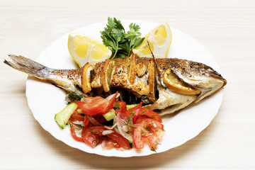 Cooked fish sea bream fish with lemon, parsley,garlic.