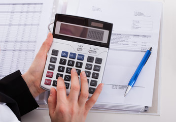 Businesswoman Using Calculator At Office Desk